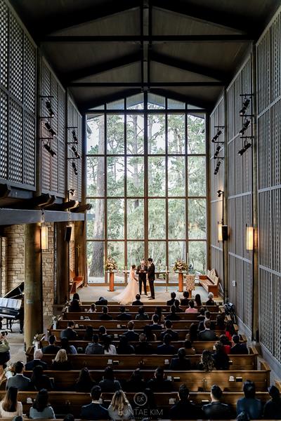 Wedding view of bride and groom in front of giant windows looking out at forest at Church in the Forest Pebble Beach 