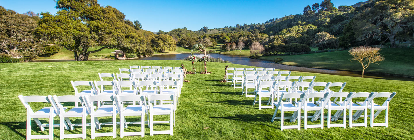 Outdoor wedding venue at Quail Meadows on bright green grass surrounded by oak trees and blue skies