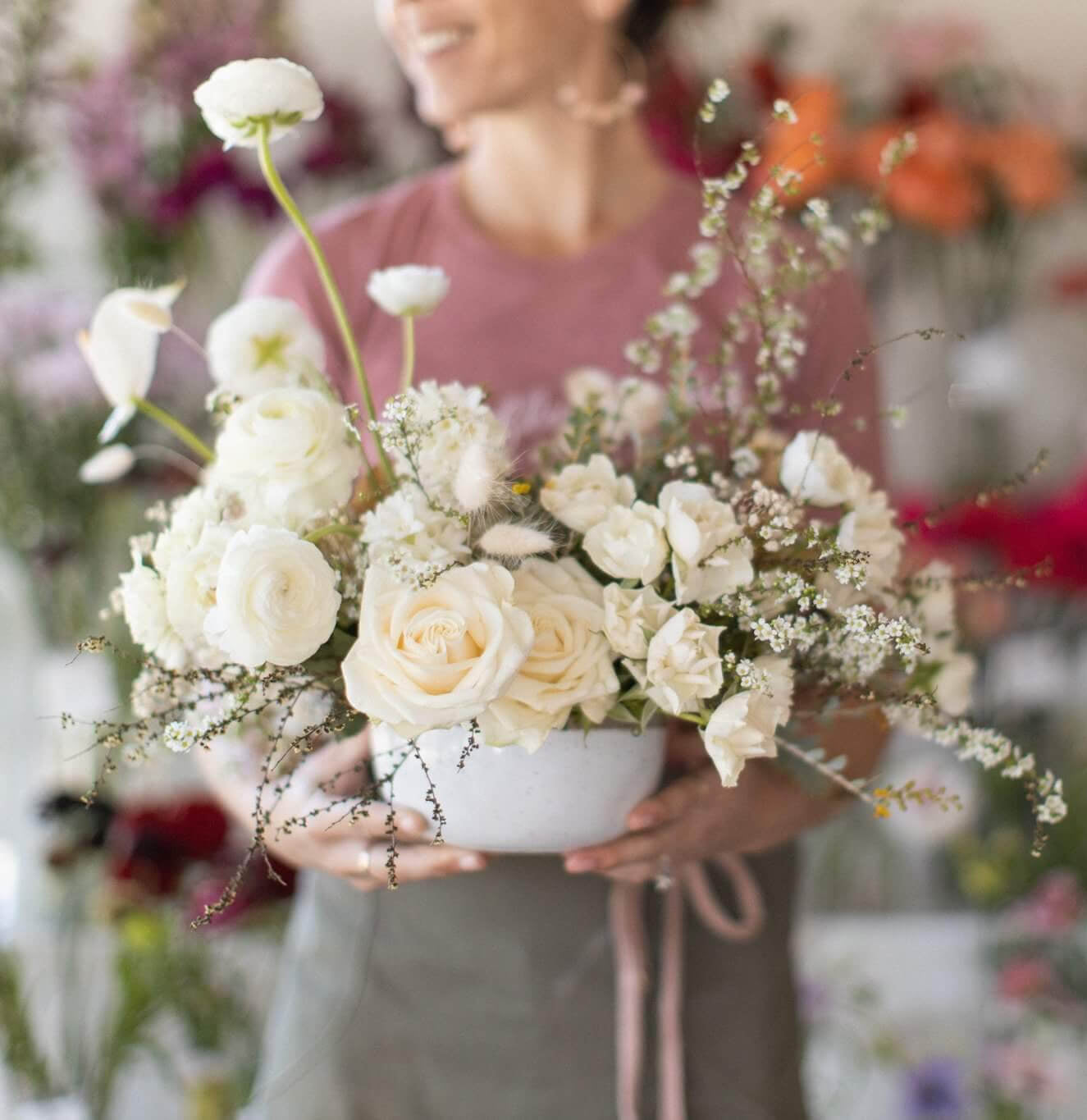 Carmel florist holding white and green sympathy flowers for delivery throughout Carmel, Pebble Beach, Pacific Grove and Monterey.