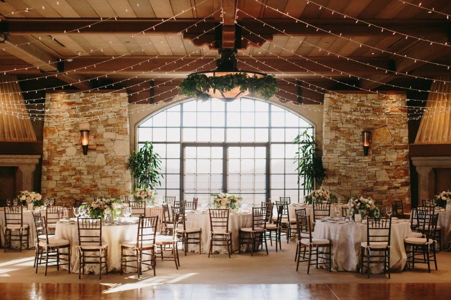 Wedding reception in the vast club house ballroom at Tehama Golf Club with a floral chandelier and walk in fireplaces